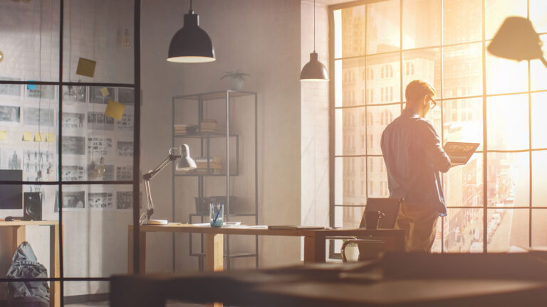 man entrepreneur standing by window in office space